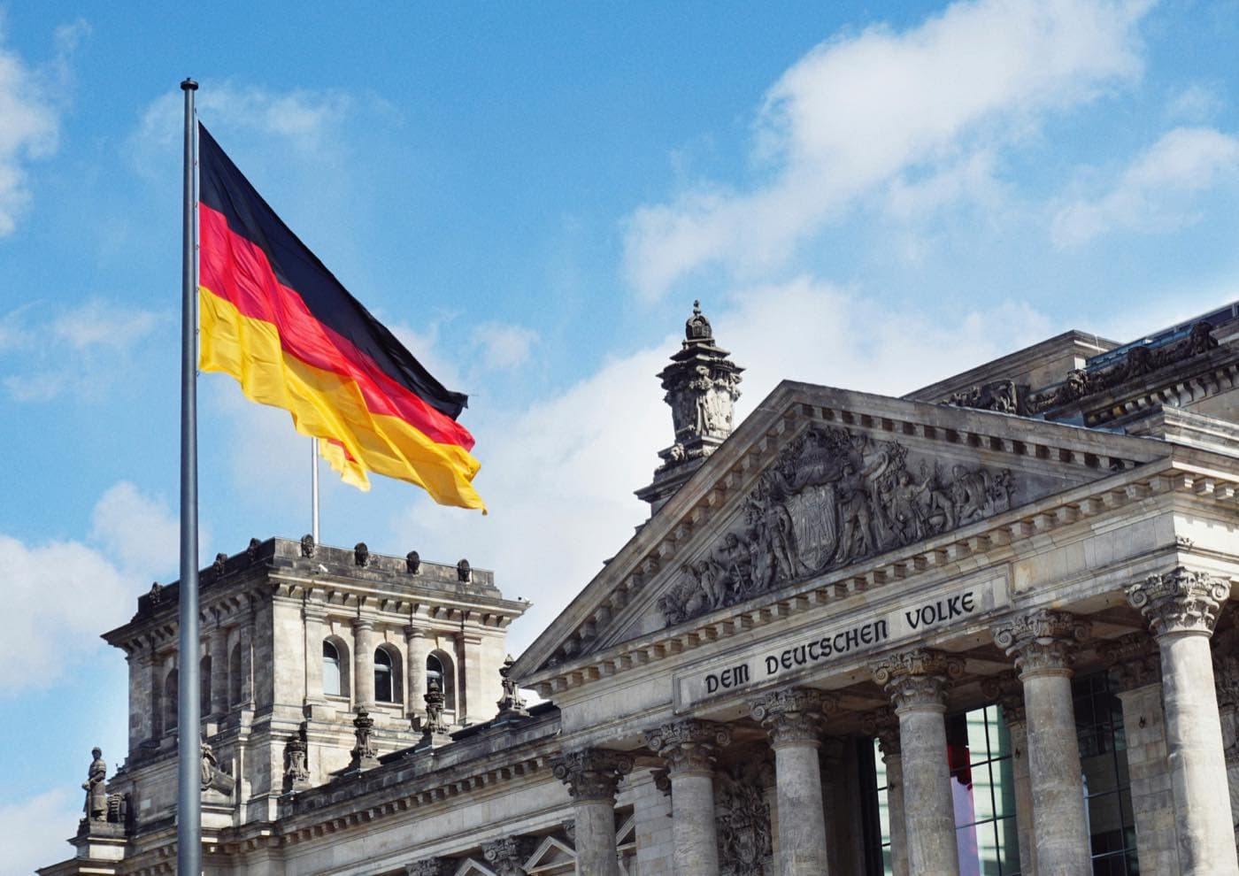 The German flag flying in front of the Reichstag building in Berlin