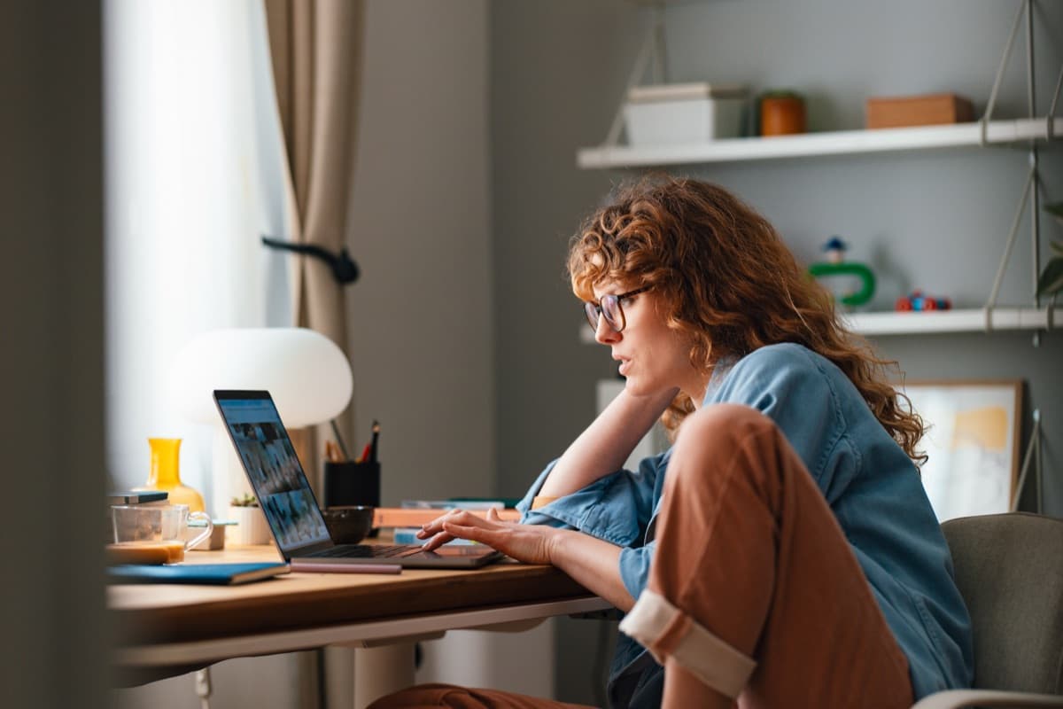 A woman working on a laptop at a desk in her flat