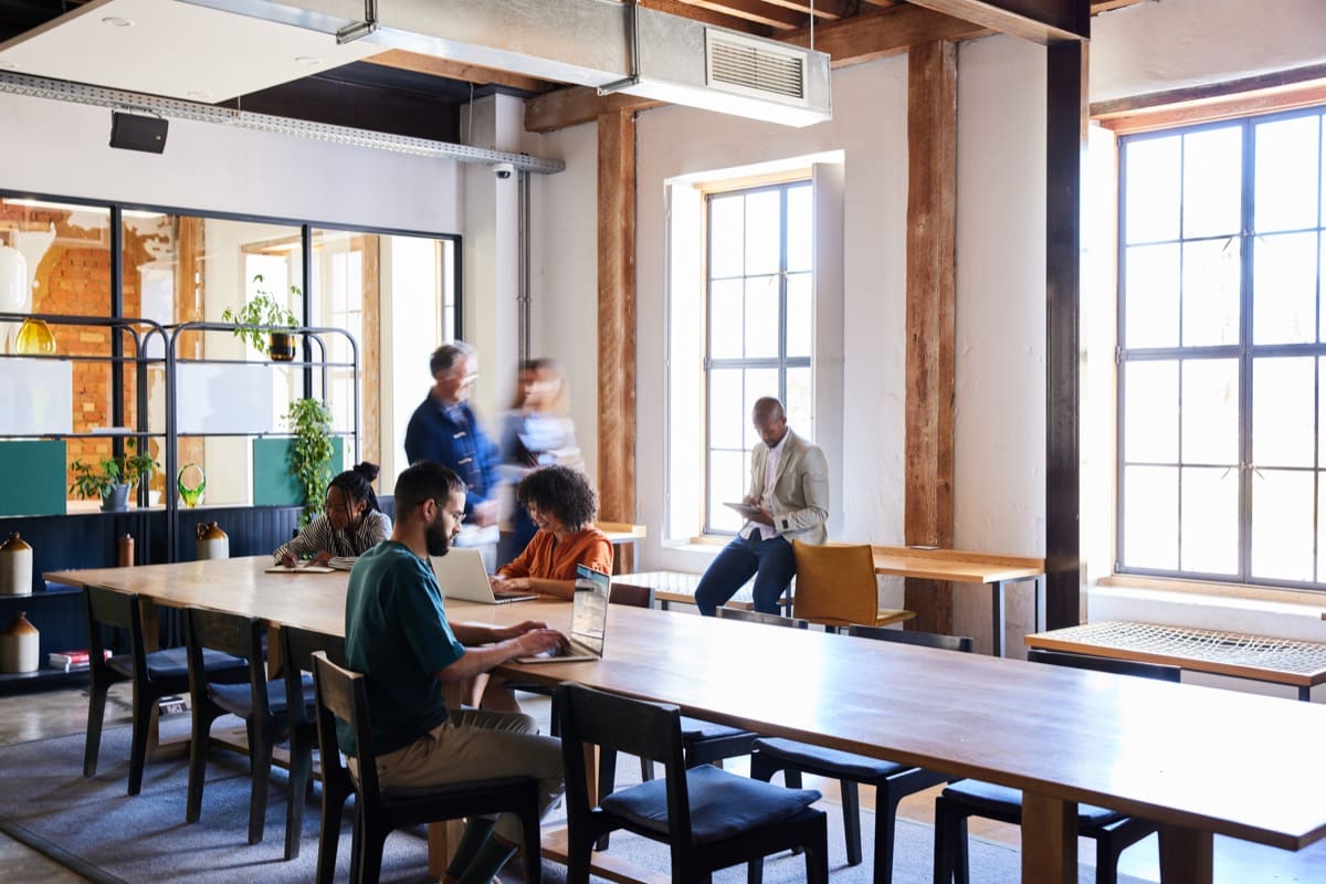 Modern coworking space with people working at shared tables