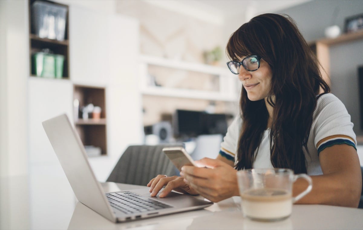 Woman completing online verification on laptop and phone